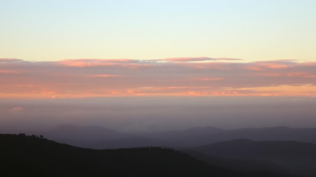 Cielo amplio al amanecer sobre colinas con nubes doradas
